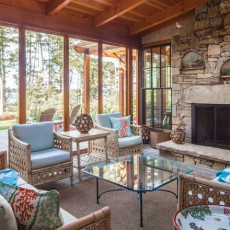 The screened porch in this Littlejohn Island home contains furnishings from Simply Home in Falmouth, ME, bark lanterns from Dwellings and antique oil paintings from Pillars