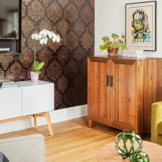 corner of the living area showcases a Fruits of Design wallpaper that’s a modern take on traditional damask