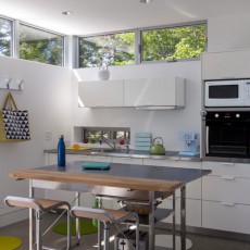 Tenants Harbor ultra modern, prefab home features a small, horizontal sink window which echoes the clerestory windows, and do the horizontal cabinets
