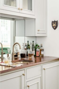 a bar area with a copper sink and faucet and white cabinets