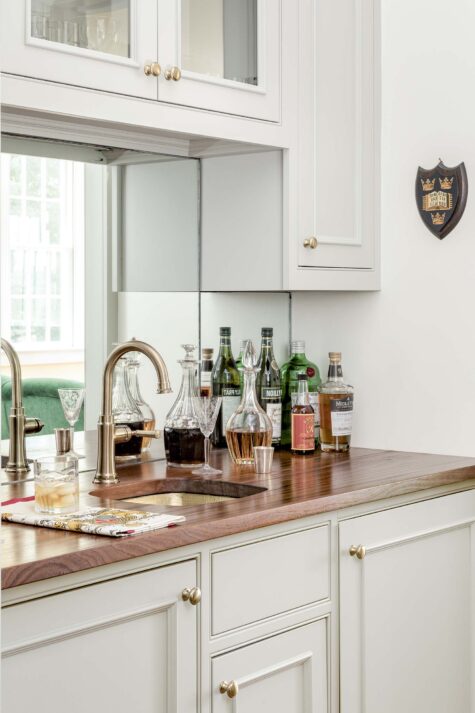 a bar area with a copper sink and faucet and white cabinets