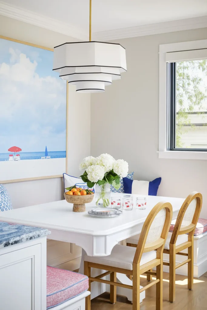 In the breakfast nook a built-in banquette and Four Hands chairs offer seating at a Lexington Home Brands table, all under a Hudson Valley Lighting fixture.